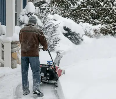 Residential snow removal technician using a snow blower to clear a home driveway and walkway in Allentown, PA